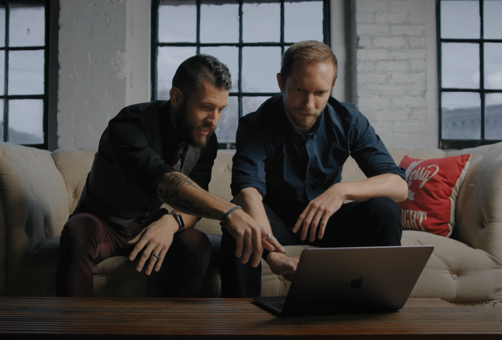 Two professionals collaborating on a laptop in an office lounge.