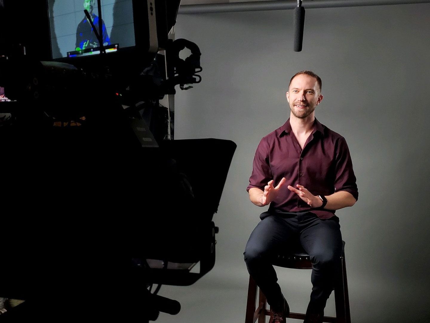 John posing on chair in front of professional camera