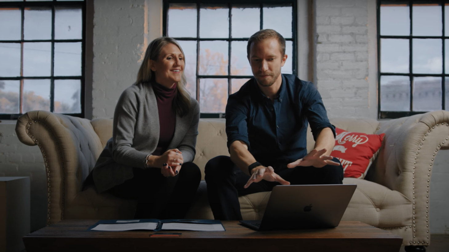Two professionals discussing over laptop in modern office.