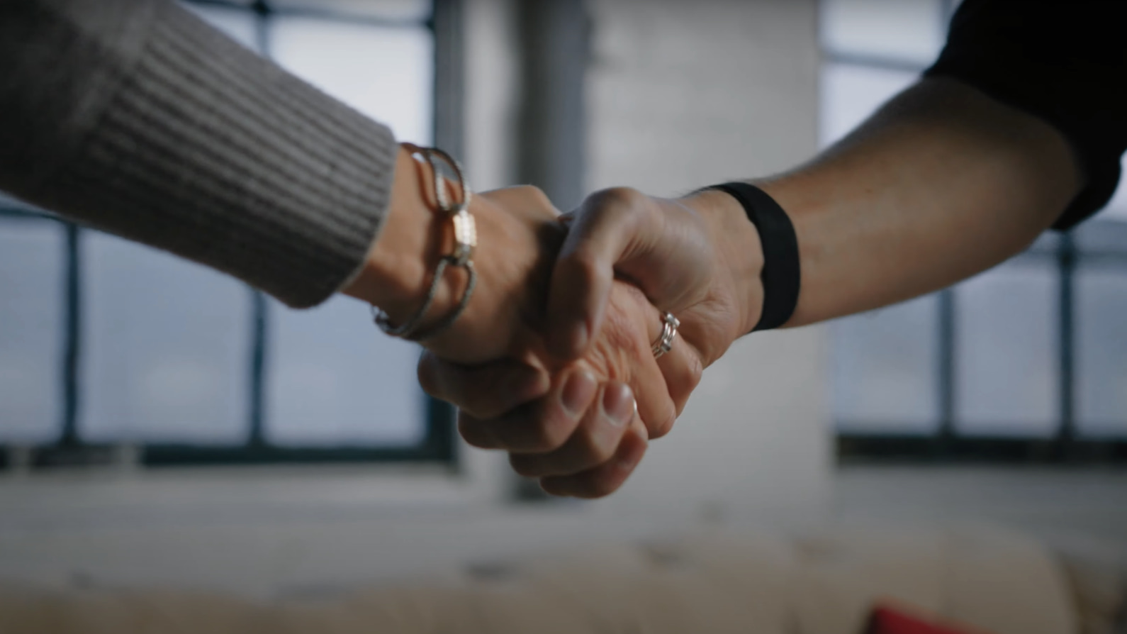 Two people fist bumping indoors for teamwork and partnership.